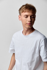 Obraz premium Young man, white t shirt, casual clothing, studio shot, neutral background, relaxed pose, calm expression, fashion, lifestyle, minimalism, clean look simple attire everyday wear casual style studio