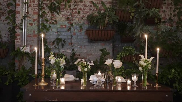 Formal Long Table Dinner In Loft, Event Planner Finalizing Seating, MaTre D Adjusting Candles, Caterer Inspecting Glassware Candlelit