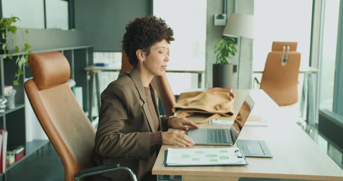 Female professional reviewing notes and opening laptop for task