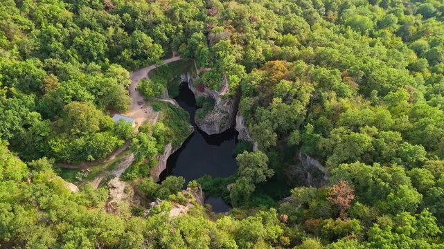 Orbital aerial view of the Tarn of Megyer-hegy, a gorgeous lake surrounded by lush forest near S&aacute;rospatak, Hungary, within a historic millstone quarry and popular nature preserve.