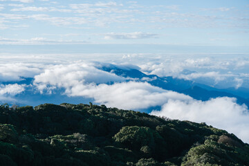 A panoramic view of lush green mountains beneath a sky filled with soft clouds, creating a serene and tranquil landscape.