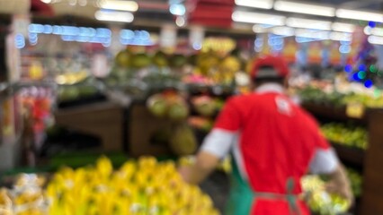 Abstract blurred and defocused background of a supermarket employee preparing bananas on the fruit...