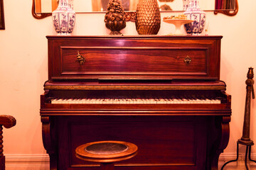 A classic wooden piano, seen in a wide view, colorful and in very good condition and preserved. Installed in a classic mansion, ready to play, with antique home decor.