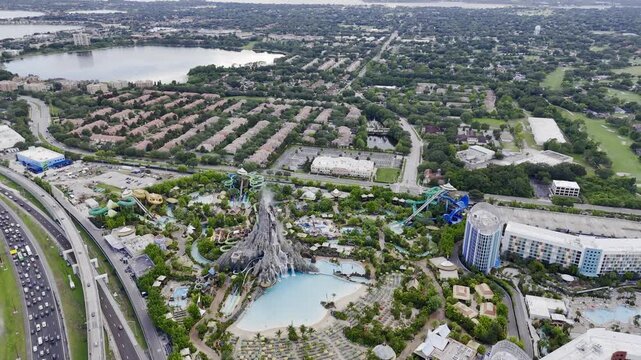 Aerial view of Volcano Bay water park with volcano, pools, slides and nearby highway traffic in Orlando, Florida, USA. g.