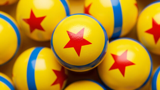 A close-up, high-angle shot features a cluster of bright yellow spheres, each decorated with a single red star in the center and a thick blue stripe circling the circumference.