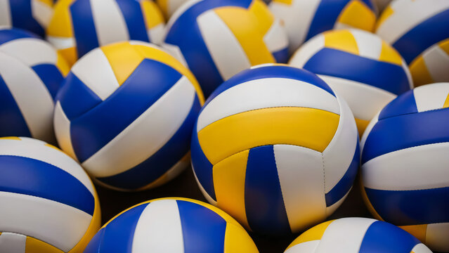 A close-up, high-angle shot features a tightly packed cluster of regulation-sized volleyballs. They are uniformly colored with panels of bright yellow, deep blue, and white.