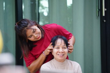An elderly woman smiles happily while receiving a head massage.