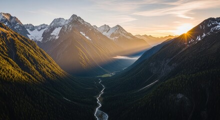 A breathtaking aerial view of a mountain range with snow-capped peaks and a winding river flowing through a lush valley at sunset.