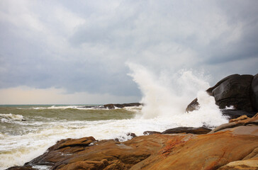 Under a cloudy sky, the waves crashed against the massive rocks, creating huge surges. (Scenic view of Hainan Stone Park, China)
