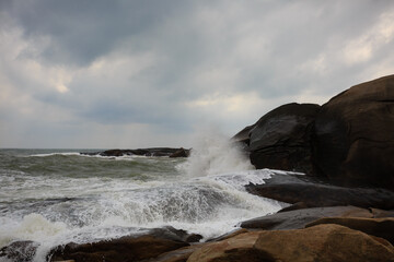 Under a cloudy sky, the waves crashed against the massive rocks, creating huge surges. (Scenic view of Hainan Stone Park, China)
