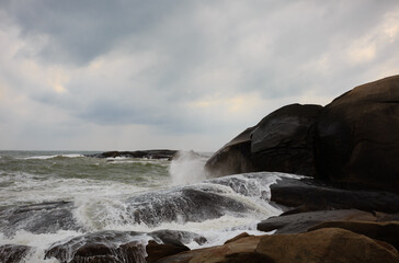 Under a cloudy sky, the waves crashed against the massive rocks, creating huge surges. (Scenic view of Hainan Stone Park, China)
