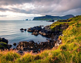 Coastal landscape features rocky cliffs, green grass, and distant mountains