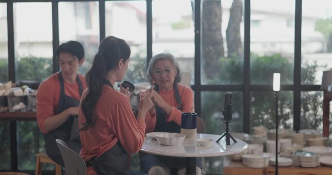 A mother, son, and daughter from a family business host a live stream, showcasing ceramic products on camera while managing orders and engagement for e commerce sales.
