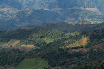 Majestic Mountain Landscape Showcasing Lush Green Terrains, Rolling Hills, and Dramatic Shadows under a Bright Sky in Remote Highlands