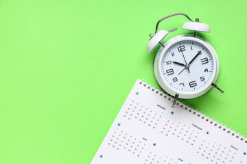 Calendar with alarm clock on green background