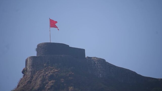 Saffron flag hoisted atop historic Pratapgad Fort, symbolizing Maratha pride, valor and heritage against the majestic Sahyadri backdrop. Built by Shivaji Maharaj, this site echoes centuries of bravery