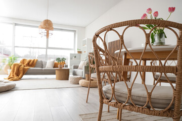 Wicker chair near dining table in modern studio apartment, closeup