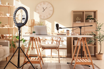 Interior of blogger's office with workplace, laptop, lamp and microphone on wooden table