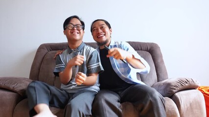 Joyful son with down syndrome watching tv with father at home