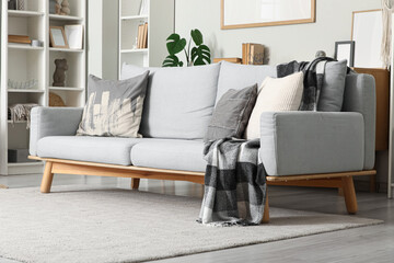 Modern interior of living room with stylish grey sofa and shelving units