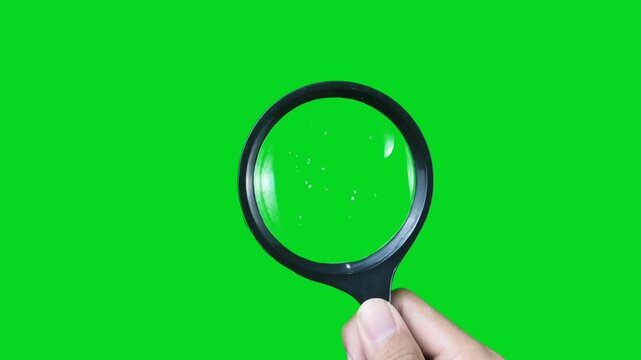 The right hand holds a magnifying glass with a green screen background