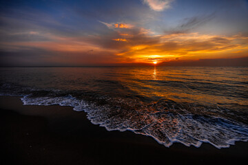 Golden sunset over calm ocean waves with dramatic clouds