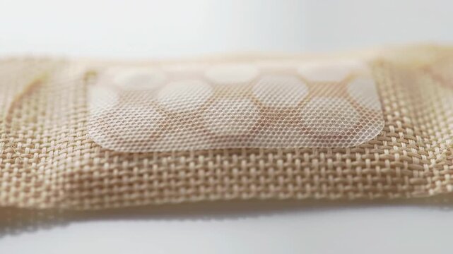 Close-up of beige fabric bandage with white gauze pad on a white surface. Medical and first aid concept showcasing wound protection and care.