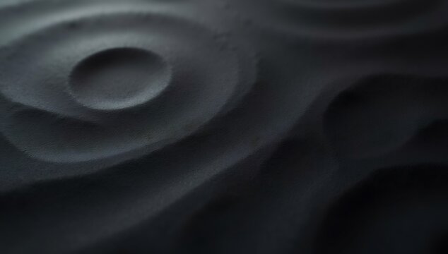 Closeup of a dark textured surface with concentric ripples and depressions creating an abstract undulating pattern