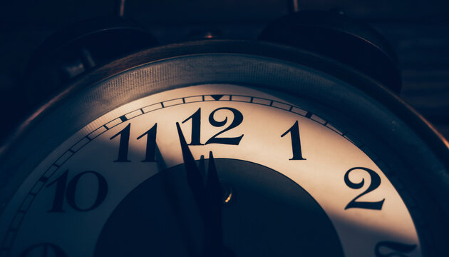 Close-up of an analog alarm clock showing almost 12 o'clock.