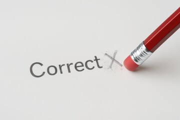 Obraz premium Red pencil erasing incorrect mark next to correct word on white paper