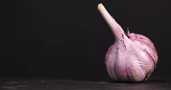 ripe purple garlic is scattered on a black table garlic spices are on a black slate board in the kitchen over cooking
