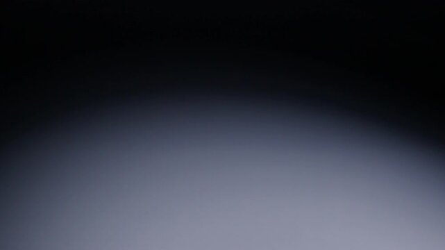 Slow-motion wide shot of red die rolling from screen right and out of shot on screen left.