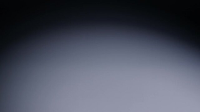 Slow-motion wide shot of white die rolling from screen right and out of shot on screen left.