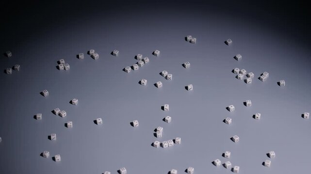 Slow-motion wide shot of a bunch of tiny dice rolling from screen right to screen left.