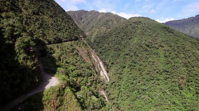 The incredibly narrow and unpaved Yungas Road, famously known as the "Death Road," winding its way through the steep, lush mountains of the Bolivian Andes.