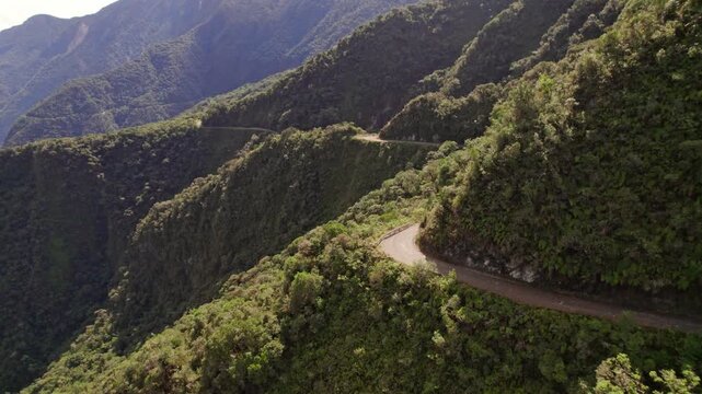 Stunning drone footage capturing the perilous, unpaved North Yungas Road in Bolivia, famous as the. The video highlights the narrow path and the steep, lush mountainsides of the Yungas region.