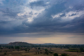 Fototapeta premium Dramatic monsoon clouds over quiet rural landscape at dusk