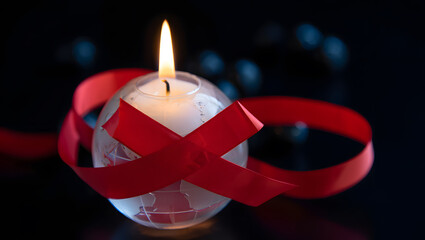 A glowing candle globe with red ribbon symbol for world aids day awareness