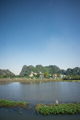 Fototapeta premium Rural Landscape with Limestone Mountains and Water Pond in Ninh Binh, Vietnam