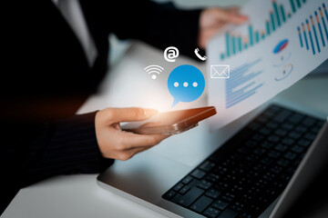 A woman is holding a cell phone and a laptop