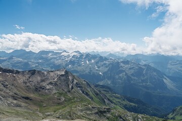 Fototapeta premium Stunning view of Austria Alps, Kaprun mountains under a blue sky with fluffy clouds. A picturesque landscape ideal for nature lovers and hiking enthusiasts, showcasing nature s beauty.