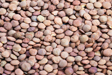 Macro shot showing earthy colored lentils with subtle hues and textures, Intimate view of textured brown lentils illuminated by warm market lighting and rustic ambiance