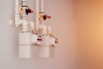 Multiple Domestic Gas Meters with White Pipes and Valves on a Wall