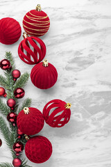 Christmas ball decor, red velvet bauble and pine branches on marble table background, top view