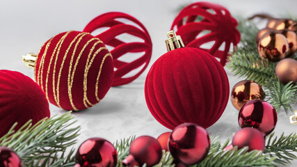 Christmas ball decorations, red velvet baubles and pine branches on marble table