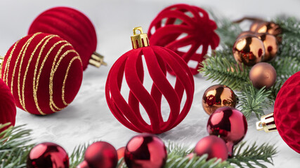 Red velvet baubles, Christmas ball ornaments and pine branches on marble table