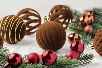 Christmas ball ornaments, brown velvet baubles and pine branches on marble table