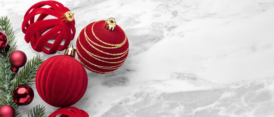 Red velvet baubles, Christmas ball ornaments and pine branches on marble table background, top view