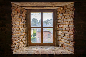 Fototapeta premium Parfondeval, Vervins, Aisne, Hauts-de-France, Grand-Est, France, August, 28th, 2025, Distant rooftops behind aged brick, Vintage brick frame reveals distant rooftops and softly illuminated interior