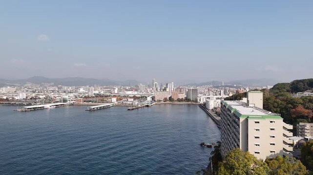 Hiroshima Port, Japan: 4K Aerial Drone Footage of Ferry Terminal, City Skyline, Hiroshima Bay, Harbour Infrastructure, Coastal Mountains and Waterfront Urban Landscape, Ujina Island and Kanawa Island
